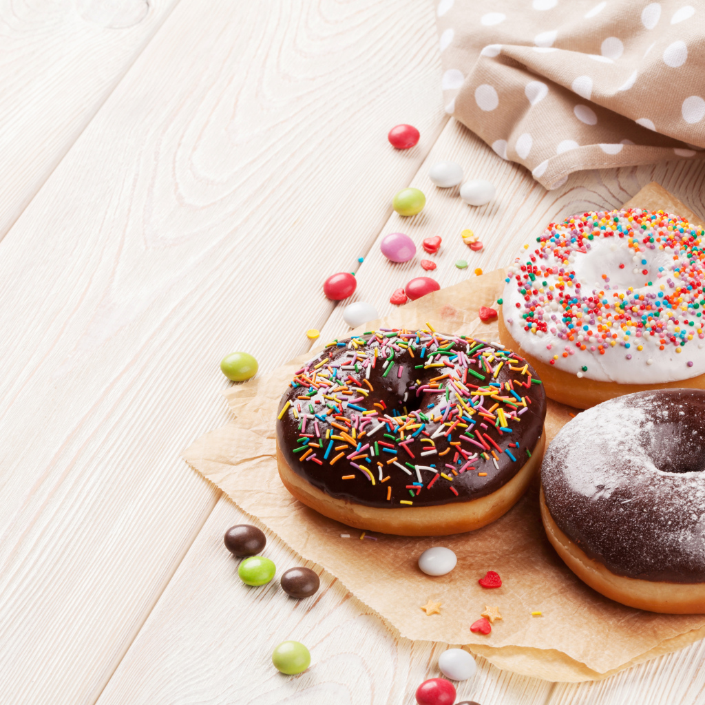 Три аппетитных пончика с глазурью на столе 