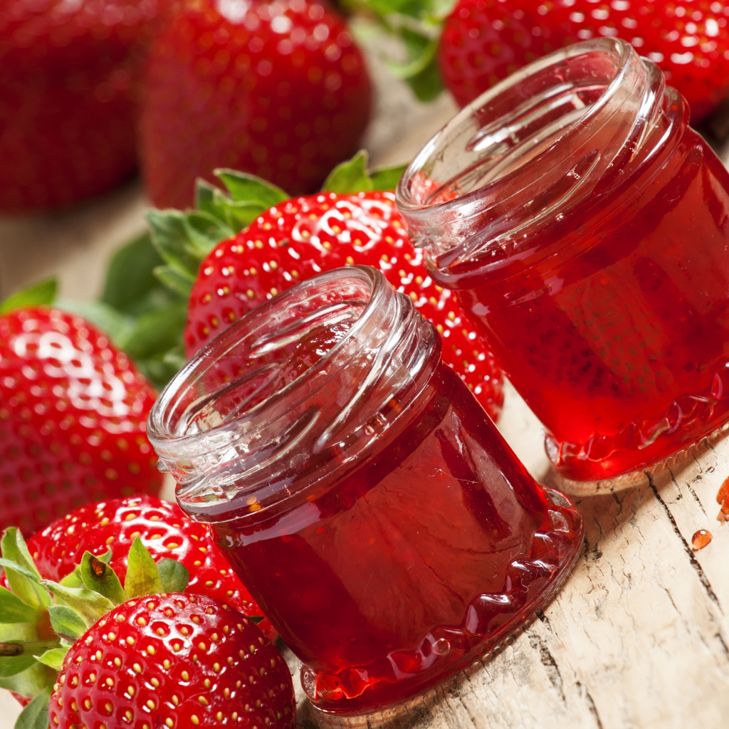 Две баночки клубничного джема на столе с клубникой