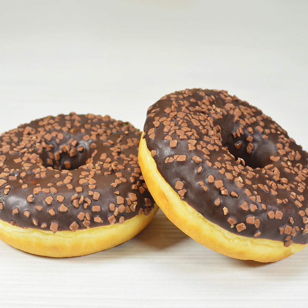 Два сладких пончика с шоколадом на сером фоне