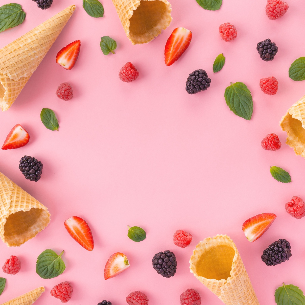 Вафельные рожки на розовом фоне с ягодами малины, клубники и ежевики