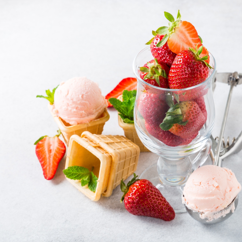 Вафельные стаканчики с мороженым на столе со свежей клубникой