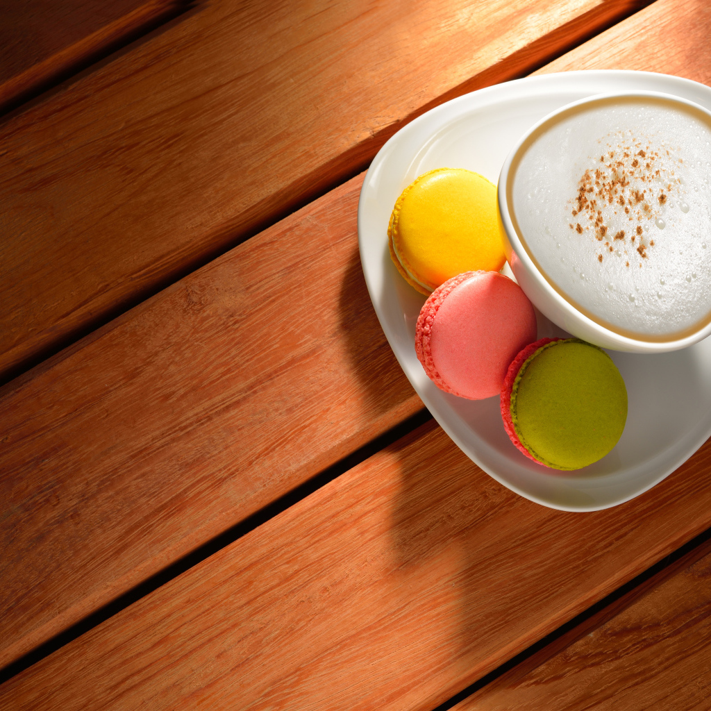 Чашка капучино на блюдце с печеньем макарон