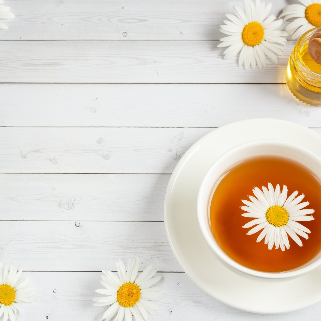 Чашка чая с ромашкой на столе с медом