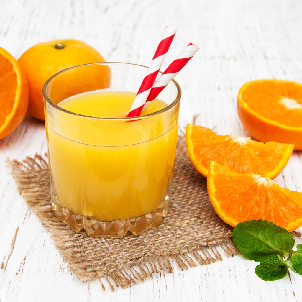 Стакан свежего сока на столе с апельсинами