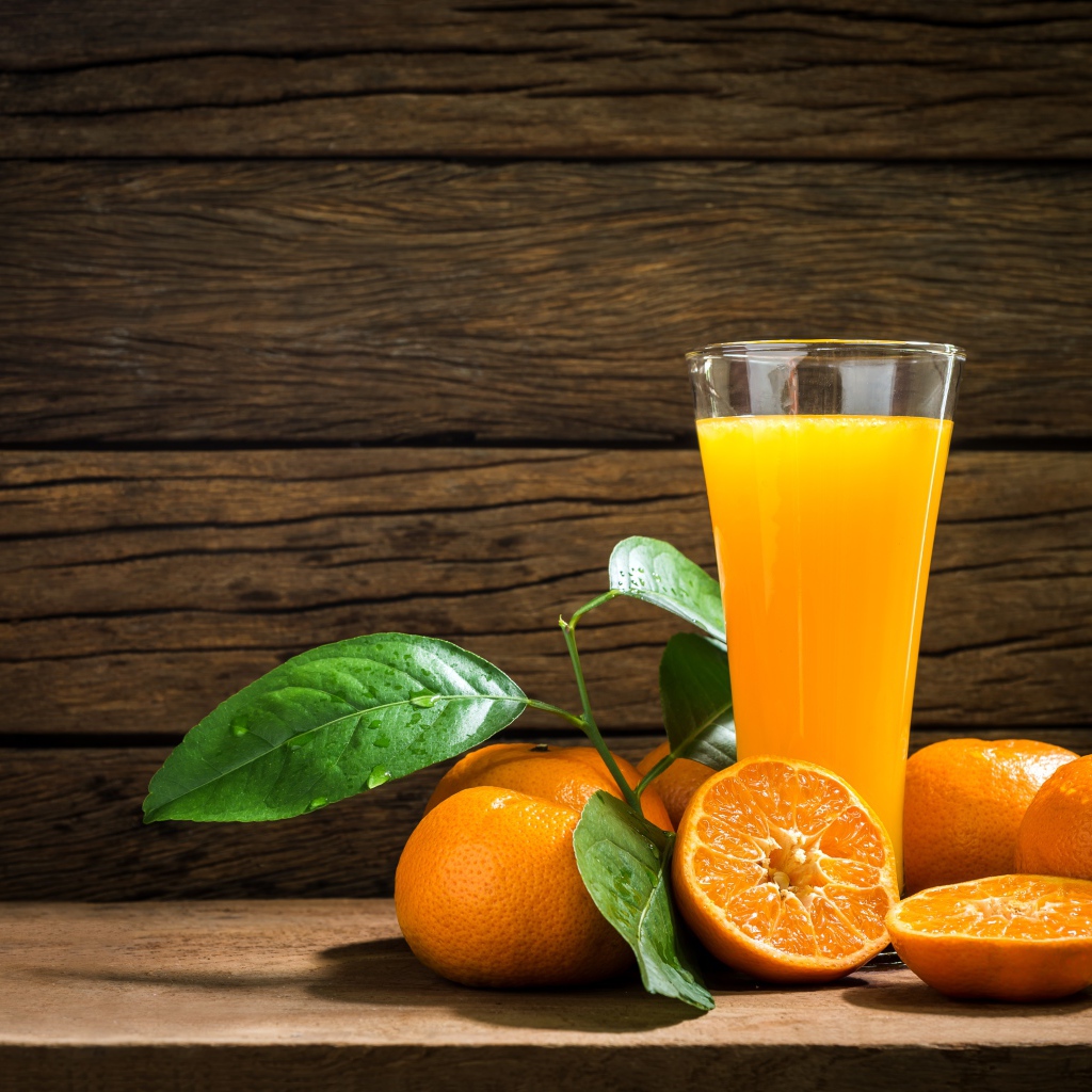 Стакан апельсинового сока на столе с мандаринами