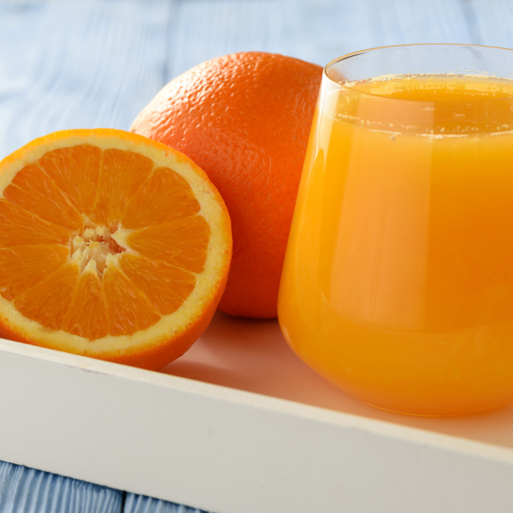 Стакан апельсинового сока на столе с апельсином 