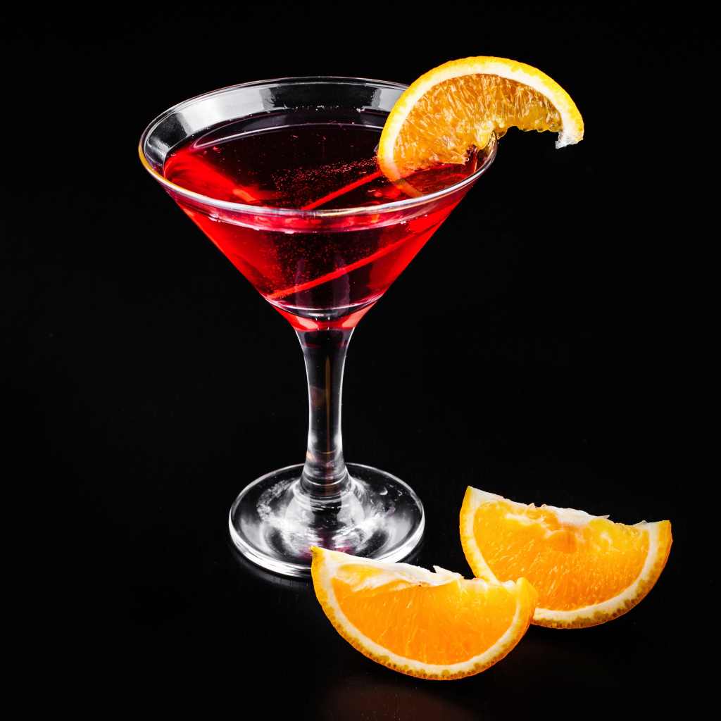Алкогольный коктейль с кусочками апельсина на черном фоне