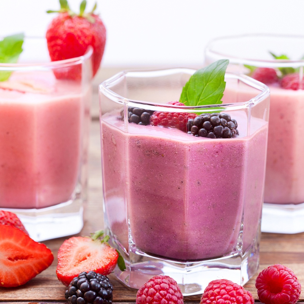 Ягодное смузи в стаканах на столе с ягодами малины, черники и клубники