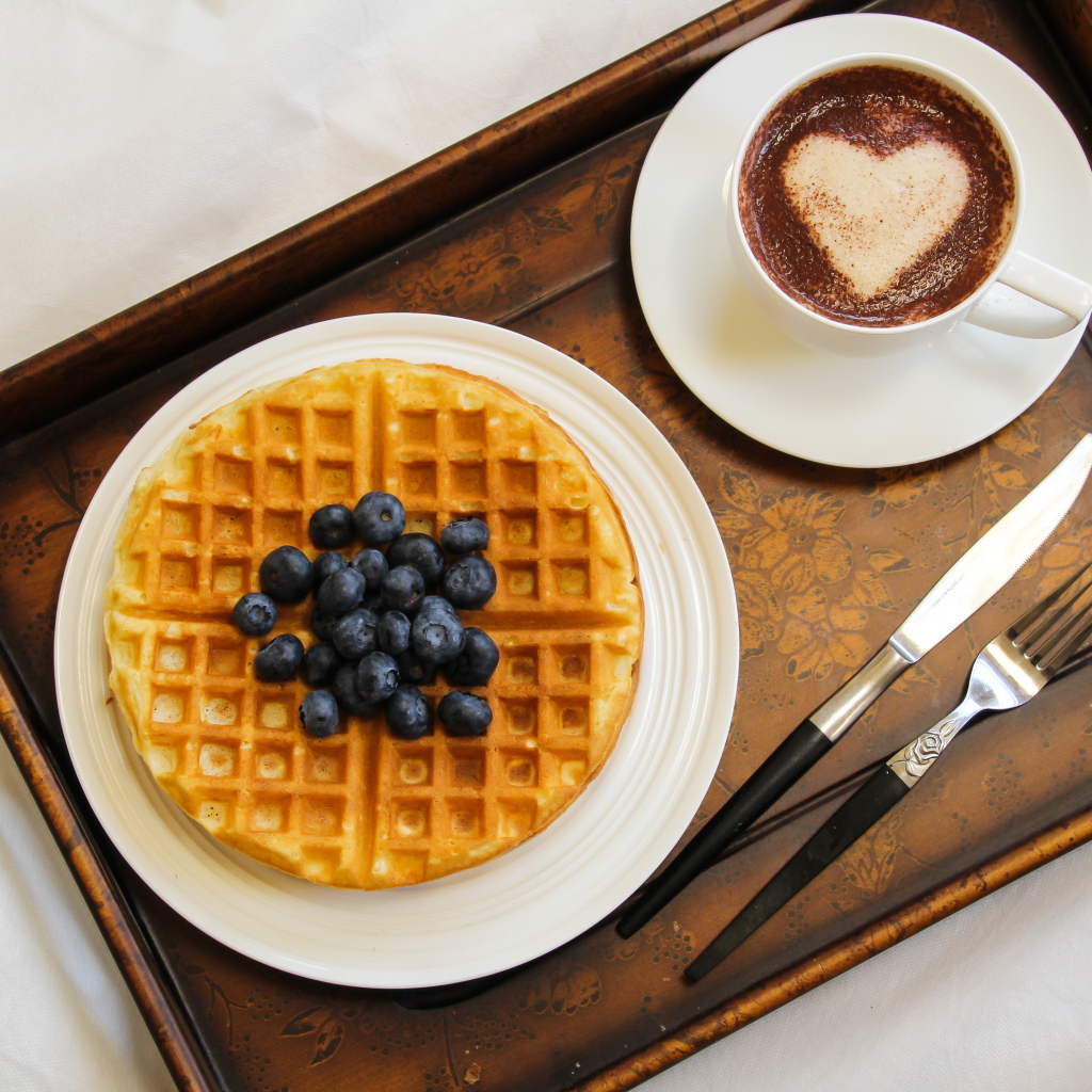 Капучино в чашке на подносе с вафлями и черникой 