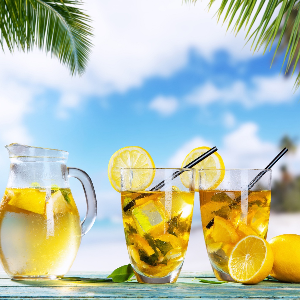 Графин и два стакана лимонада на столе на тропическом пляже