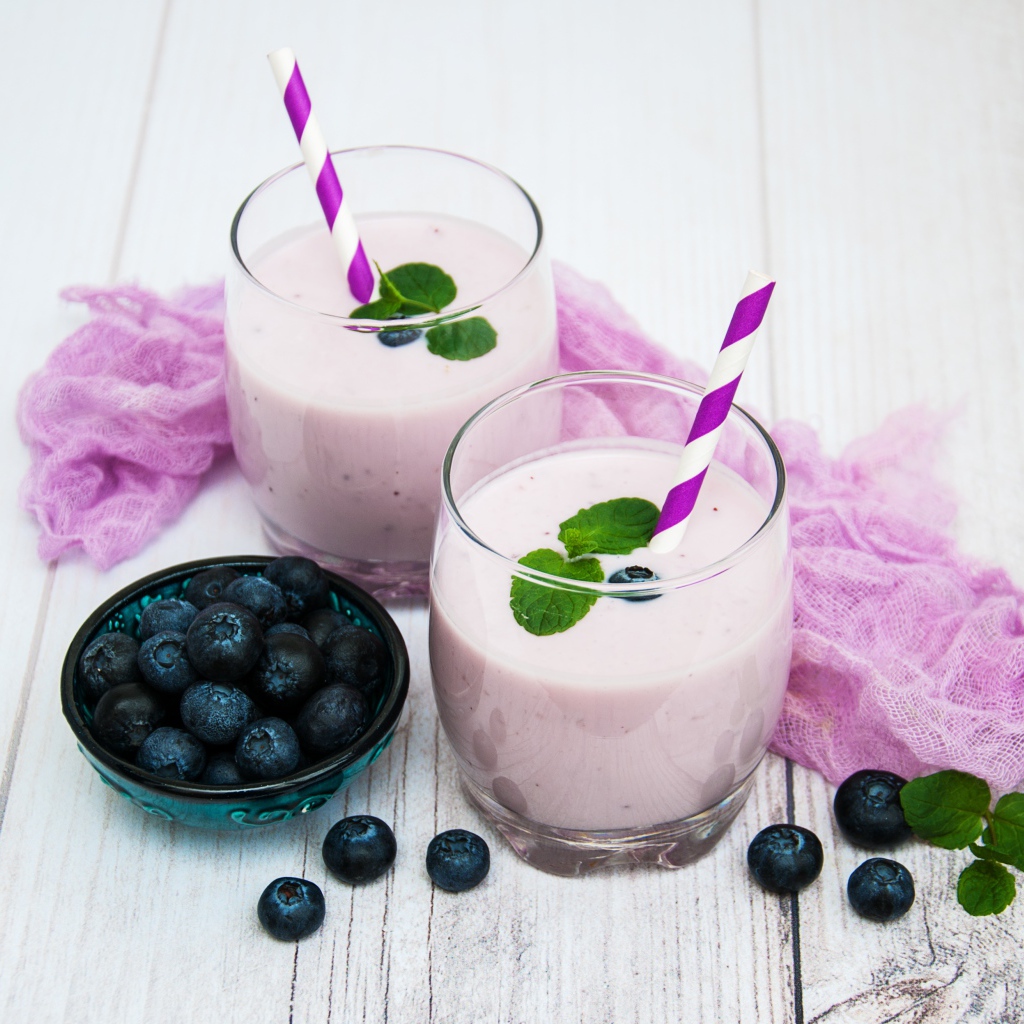 Коктейль в стаканах на столе с ягодами черники