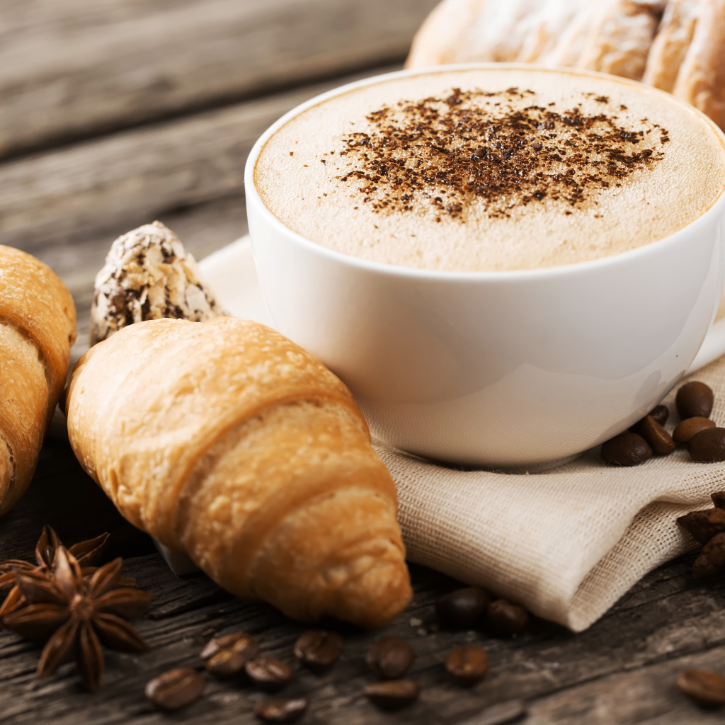 Чашка капучино на столе круассанами