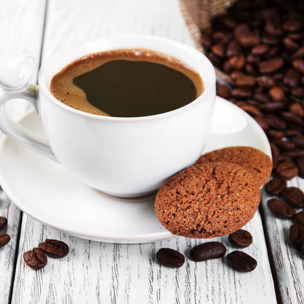 Чашка кофе на столе с кофейными зернами и печеньем