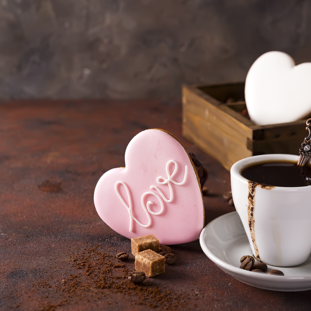 Чашка кофе на столе с сахаром и печеньем в форме сердца 
