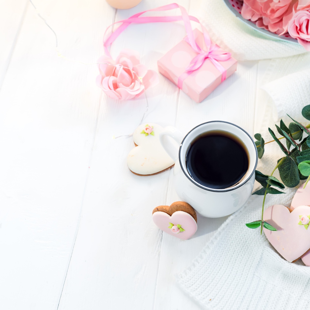 Чашка кофе на столе с печеньем в форме сердца и подарком