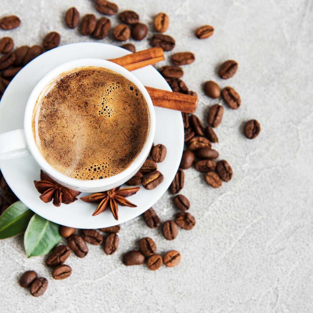 Чашка кофе с кофейными зернами на столе с корицей и бадьяном