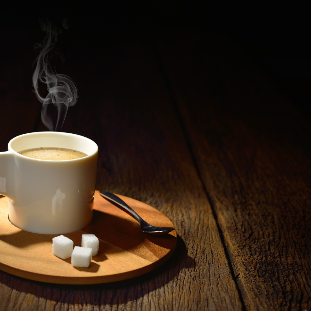 Чашка горячего кофе на столе с сахаром