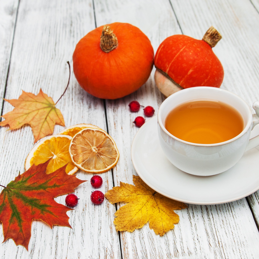 Чашка чая на столе с опавшими листьями и тыквой
