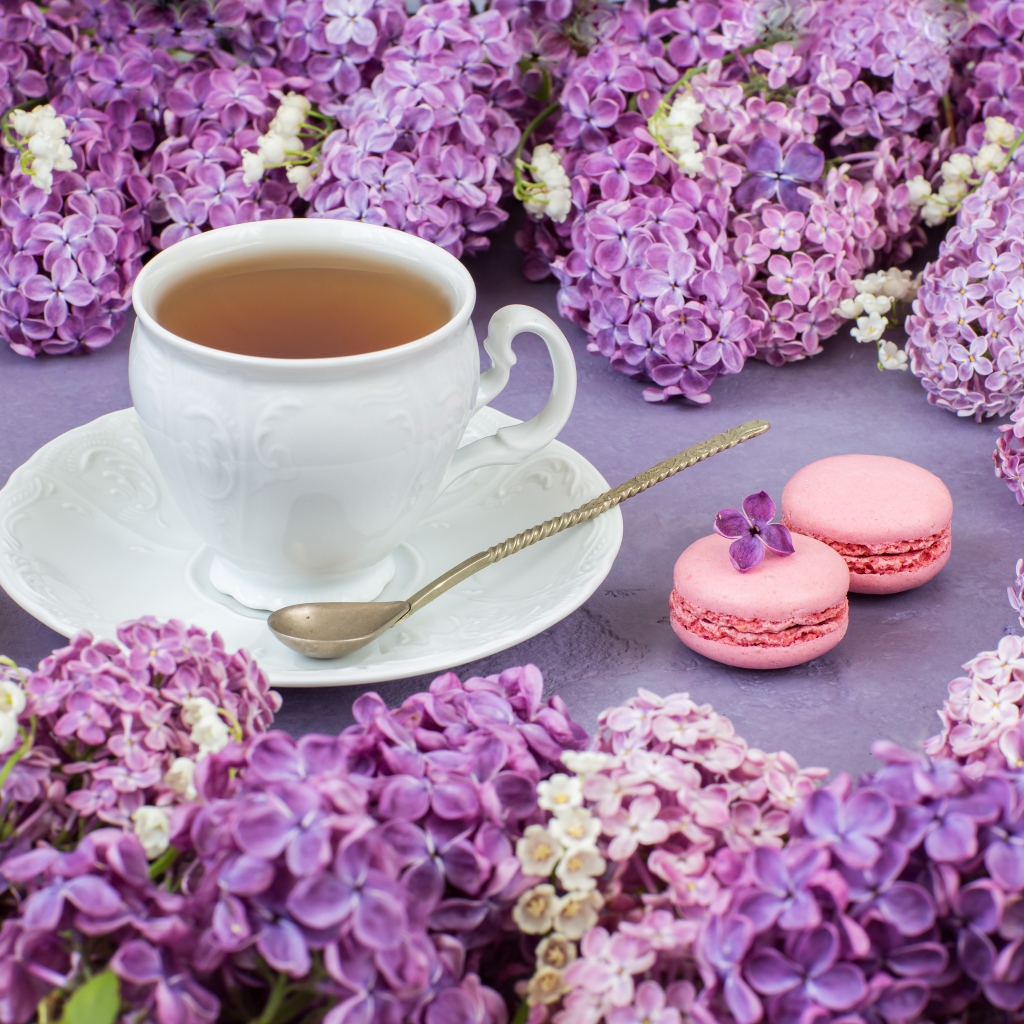 Чашка чая на столе с цветами сирени и десертом макарон