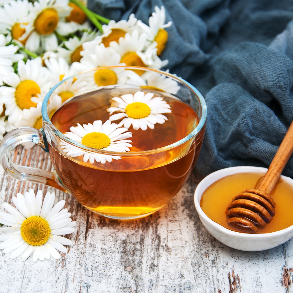 Чашка чая на столе с медом и букетом ромашек