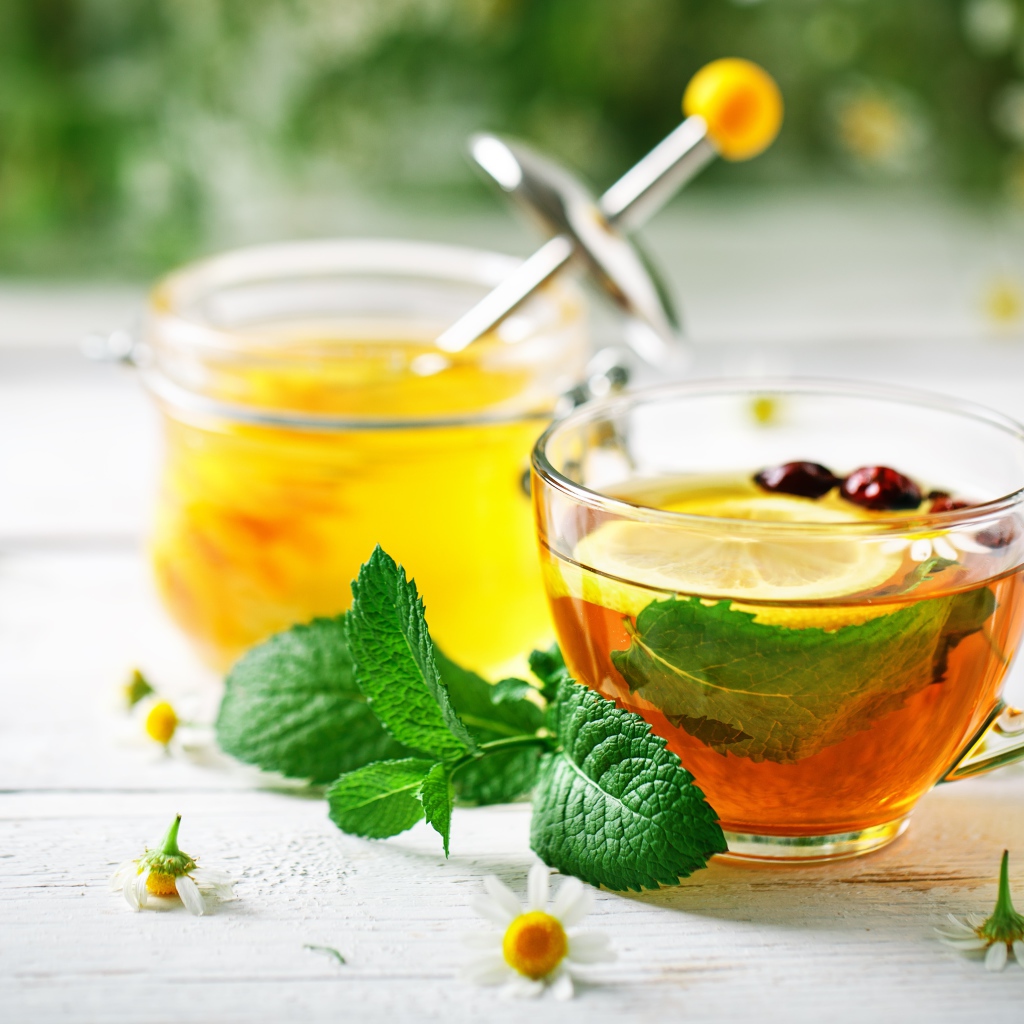 Чашка чая с лимоном и мятой на столе с медом