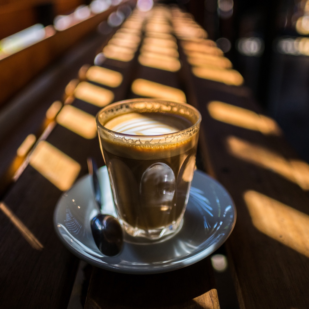 Стакан с кофе стоит на деревянном лавке