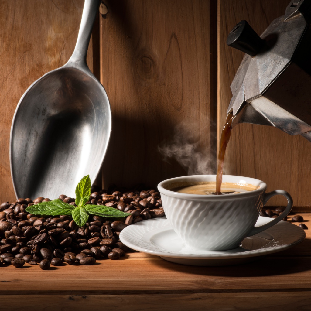 Горячий кофе наливают в белую чашку на столе с кофейными зернами