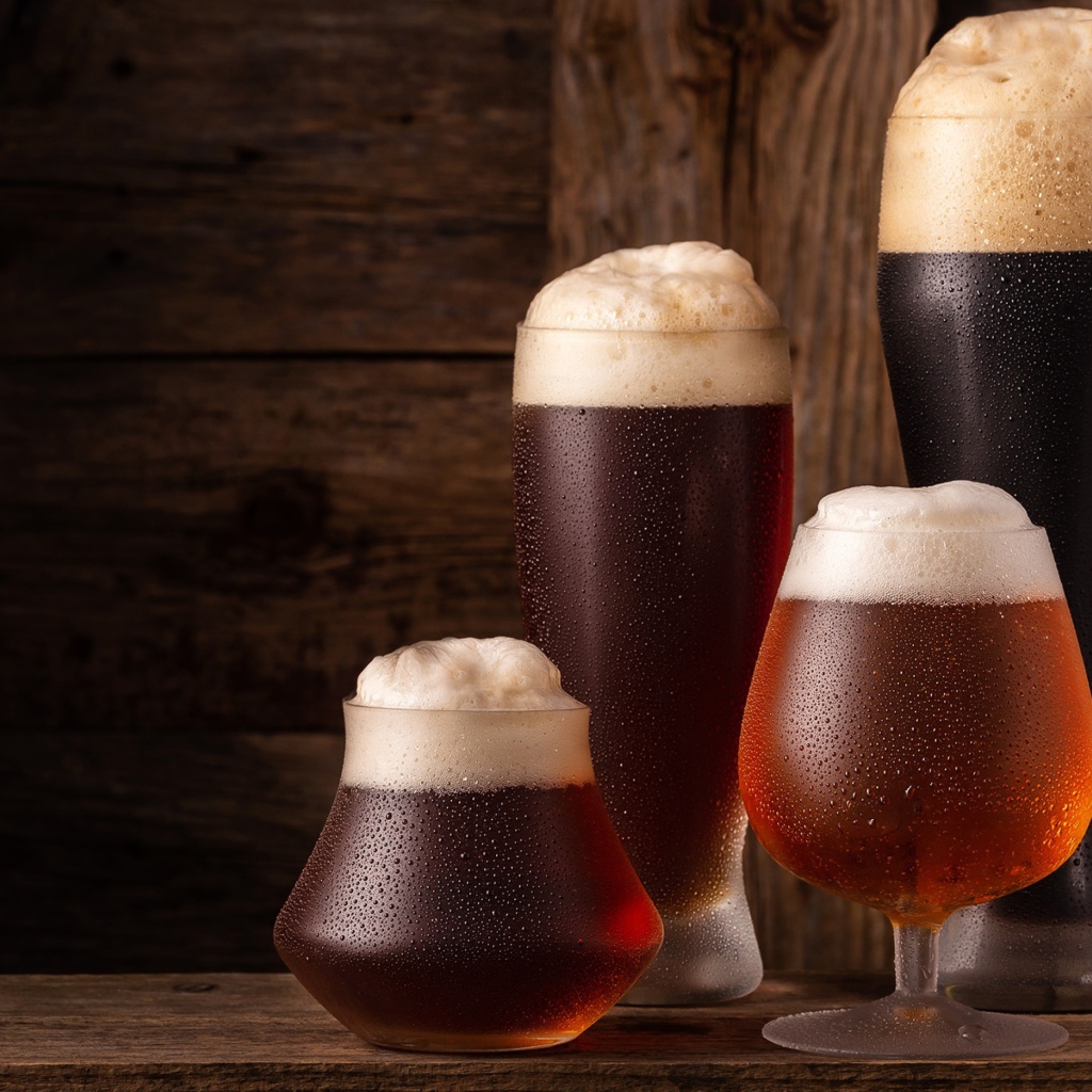 Много бокалов холодного пенного пива на столе 