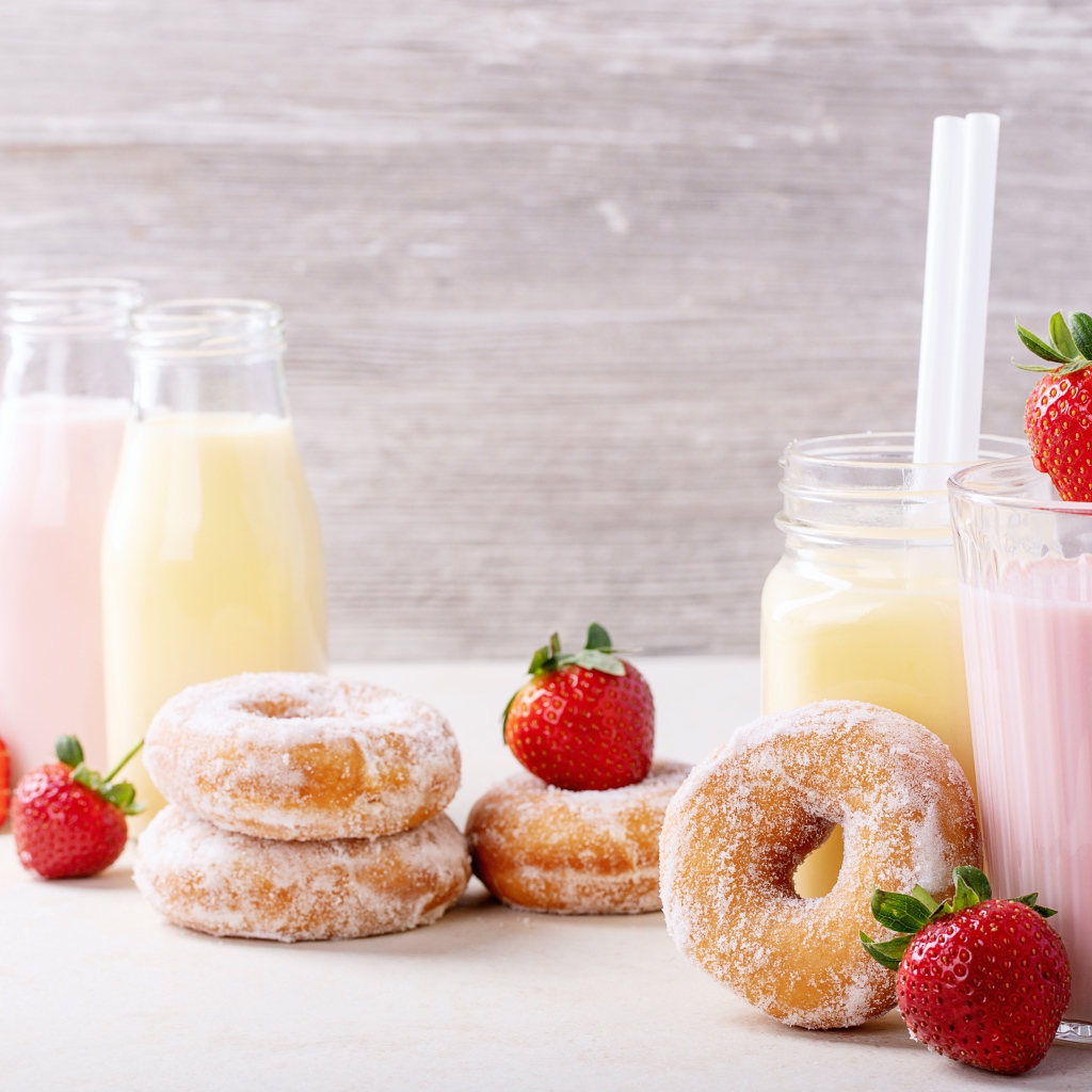 Молочные коктейли на столе с клубникой и пончиками