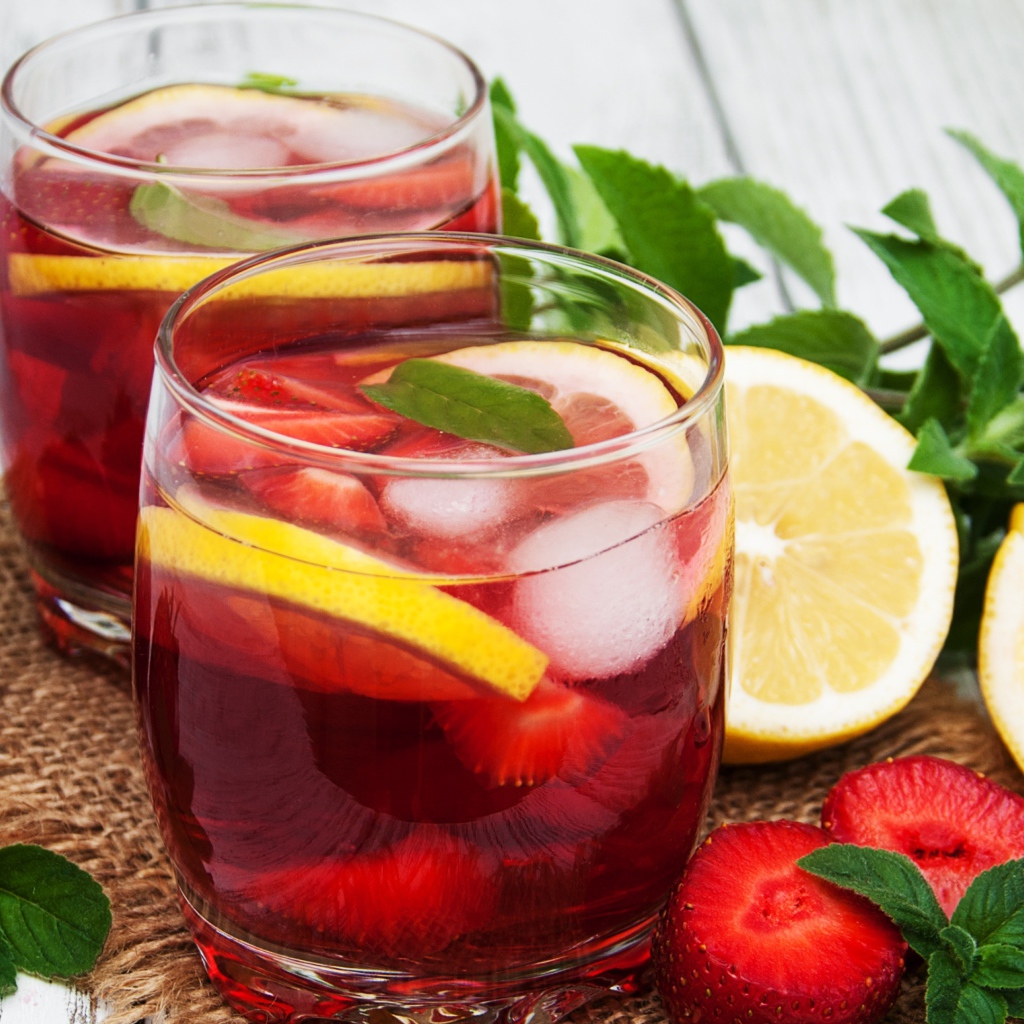 Мохито в стаканах на столе с клубникой, лимоном и мятой