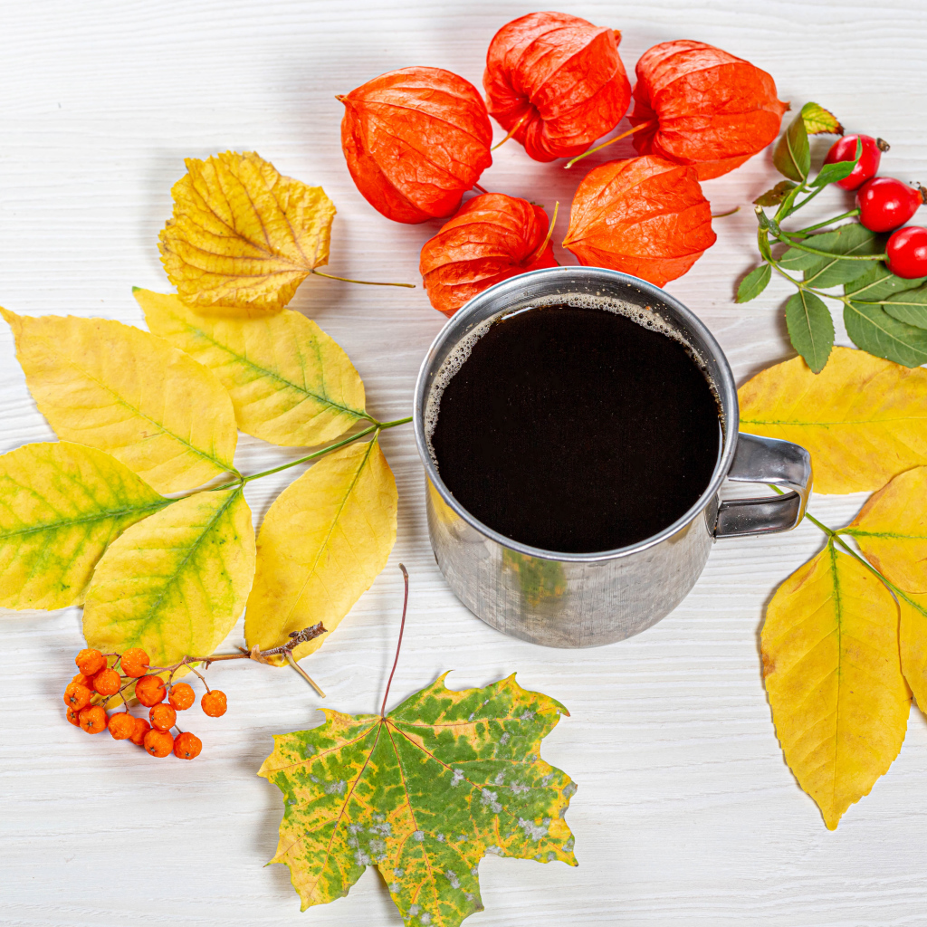 Кружка кофе на столе с осенними листьями, физалисом и шиповником