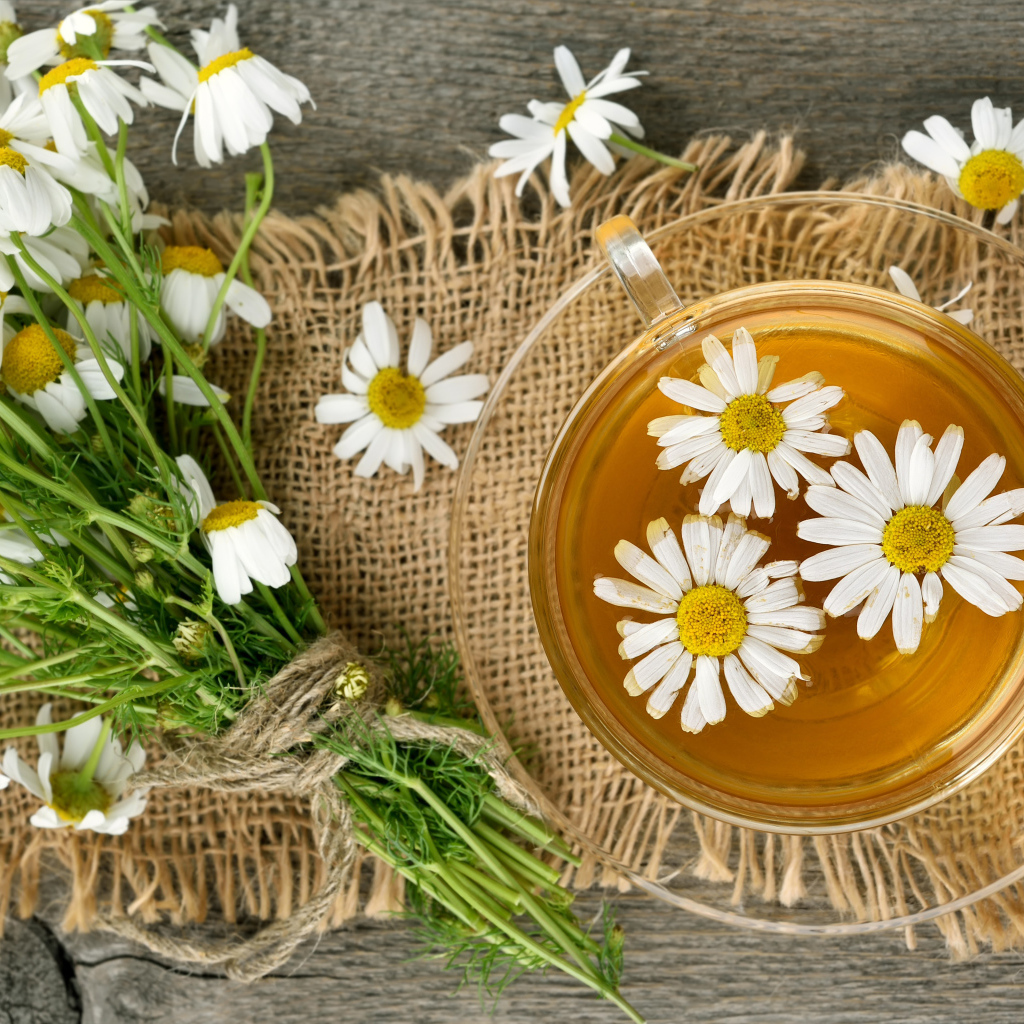 Чай в стеклянной чашке на столе с ромашкой