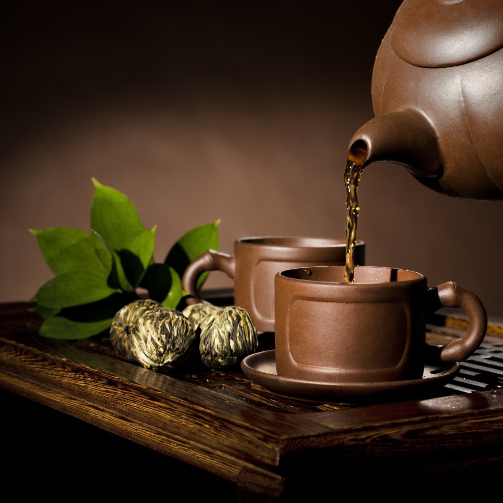 Чай наливают из чайника в коричневую чашку