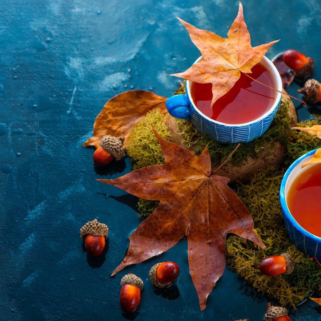 Чай на столе с осенними листьями и желудями 