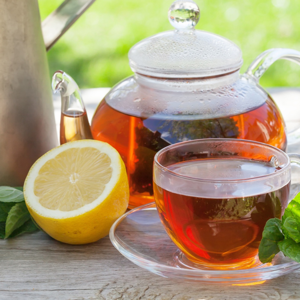 Чайник с чаем на столе с чашкой и половиной лимона