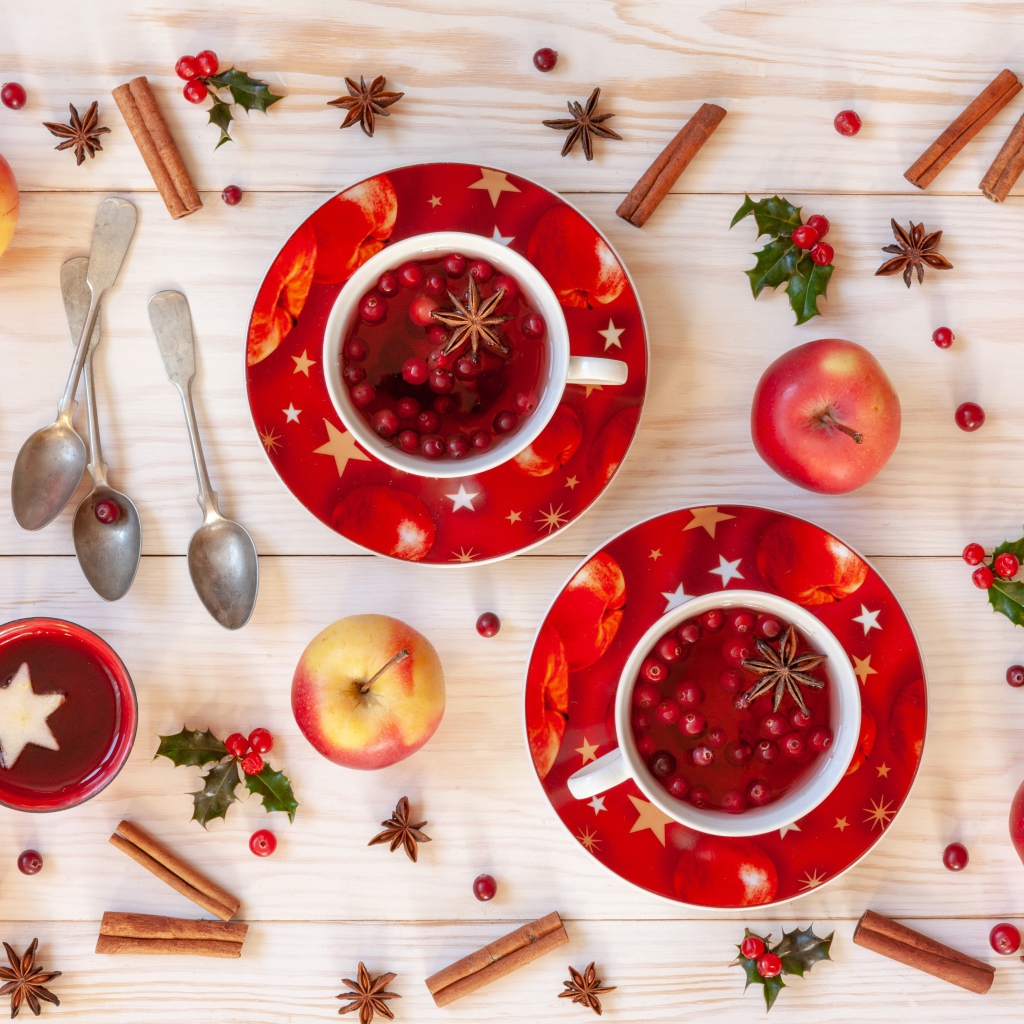 Две чашки клюквенного чая на столе с корицей, яблоками и бадьяном