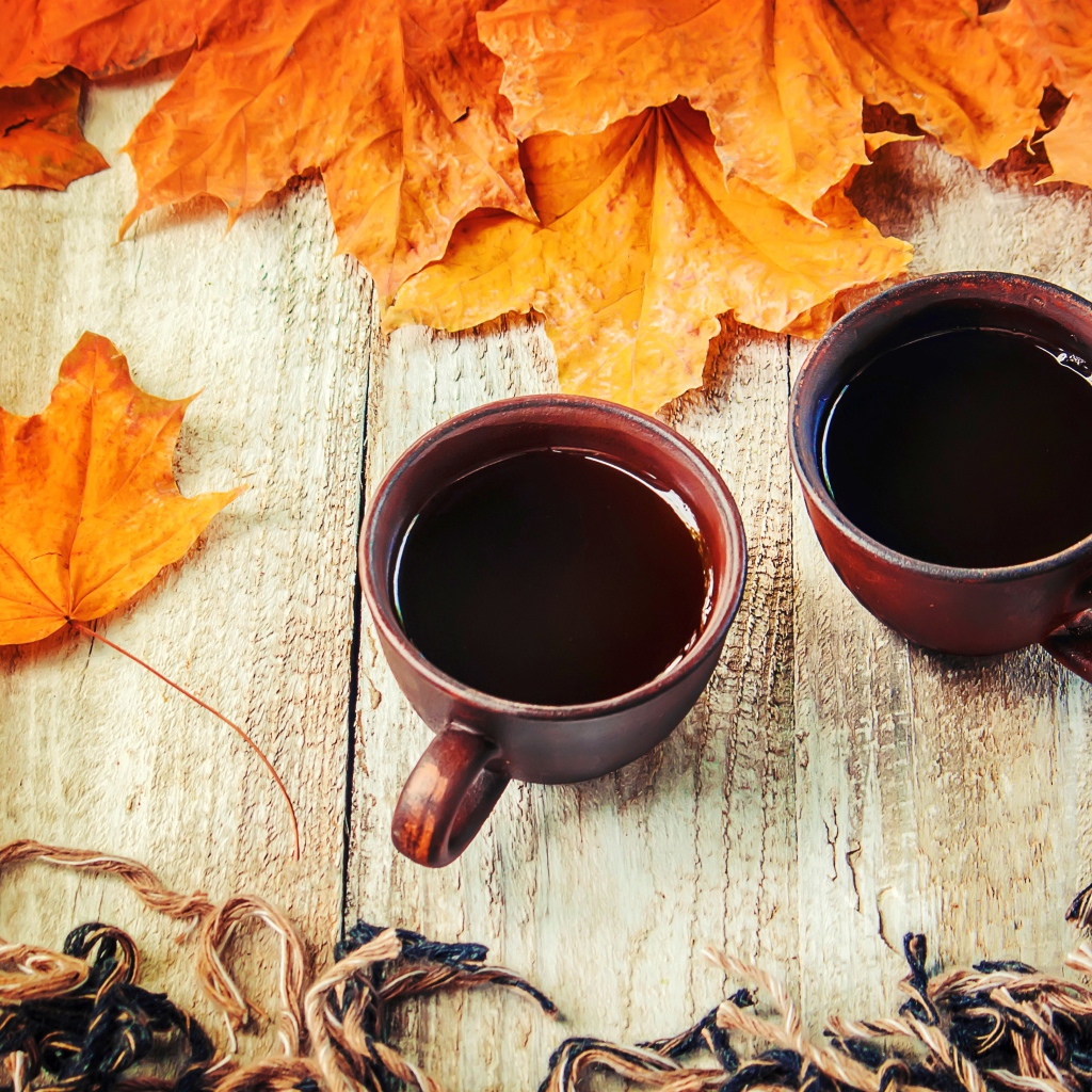 Две чашки горячего кофе на столе с сухими листьями