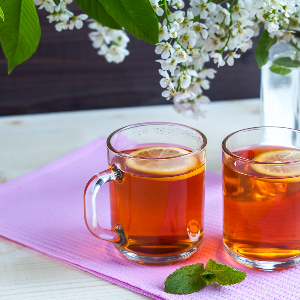 Две чашки чая с лимоном на столе с цветами 