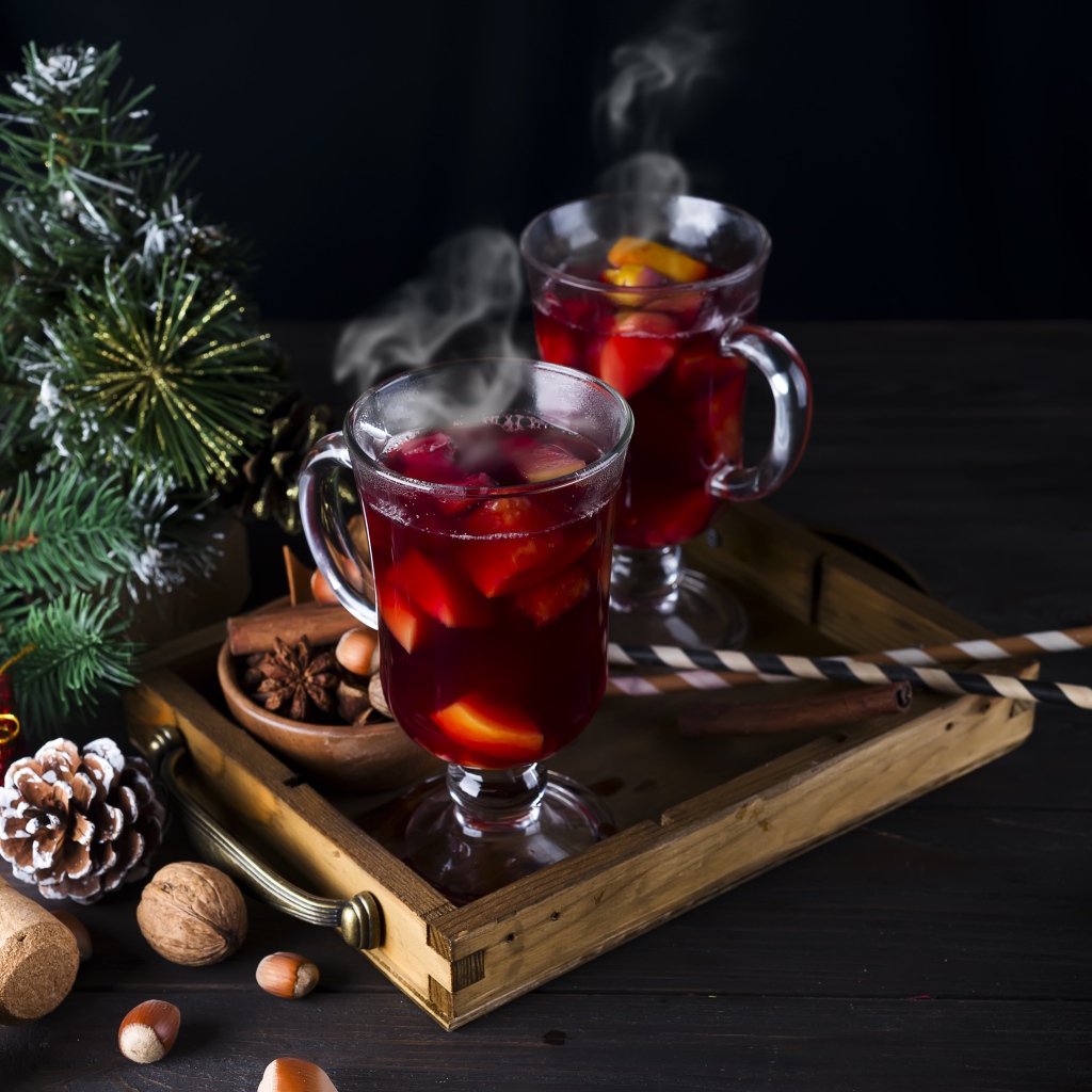 Два стакана горячего глинтвейна на столе с еловой веткой