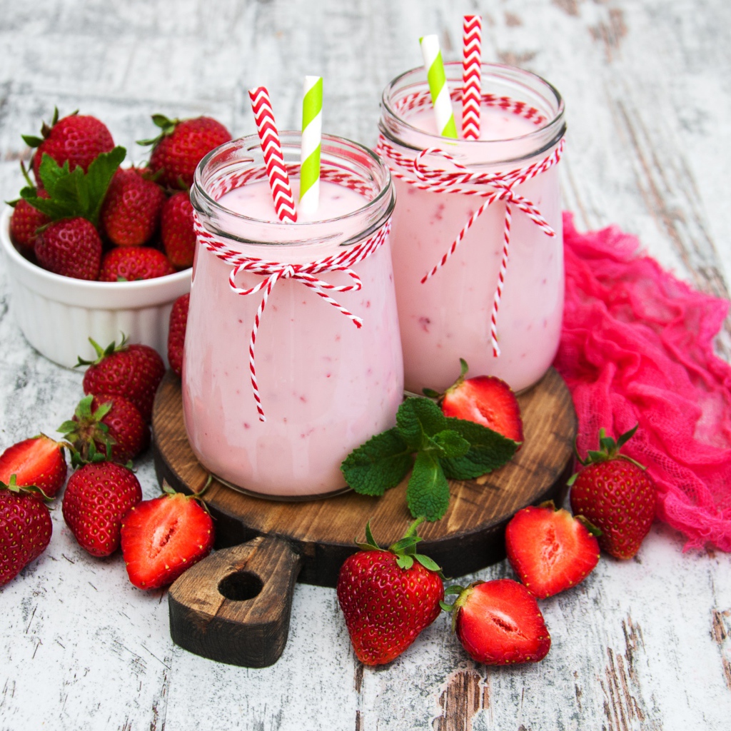 Две банки смузи стоят на доске на столе с клубникой