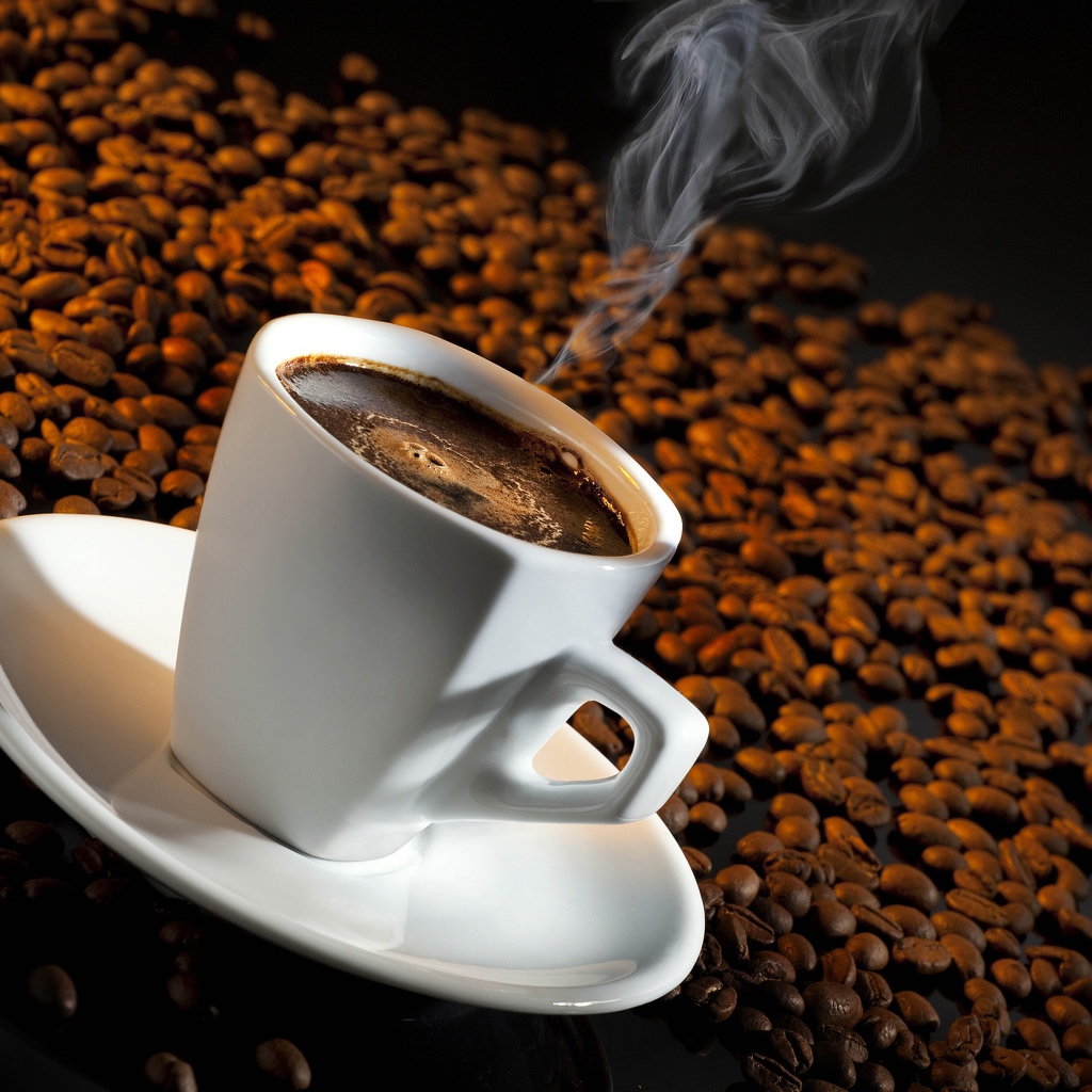 Белая чашка с кофе на черном фоне с кофейными зернами 