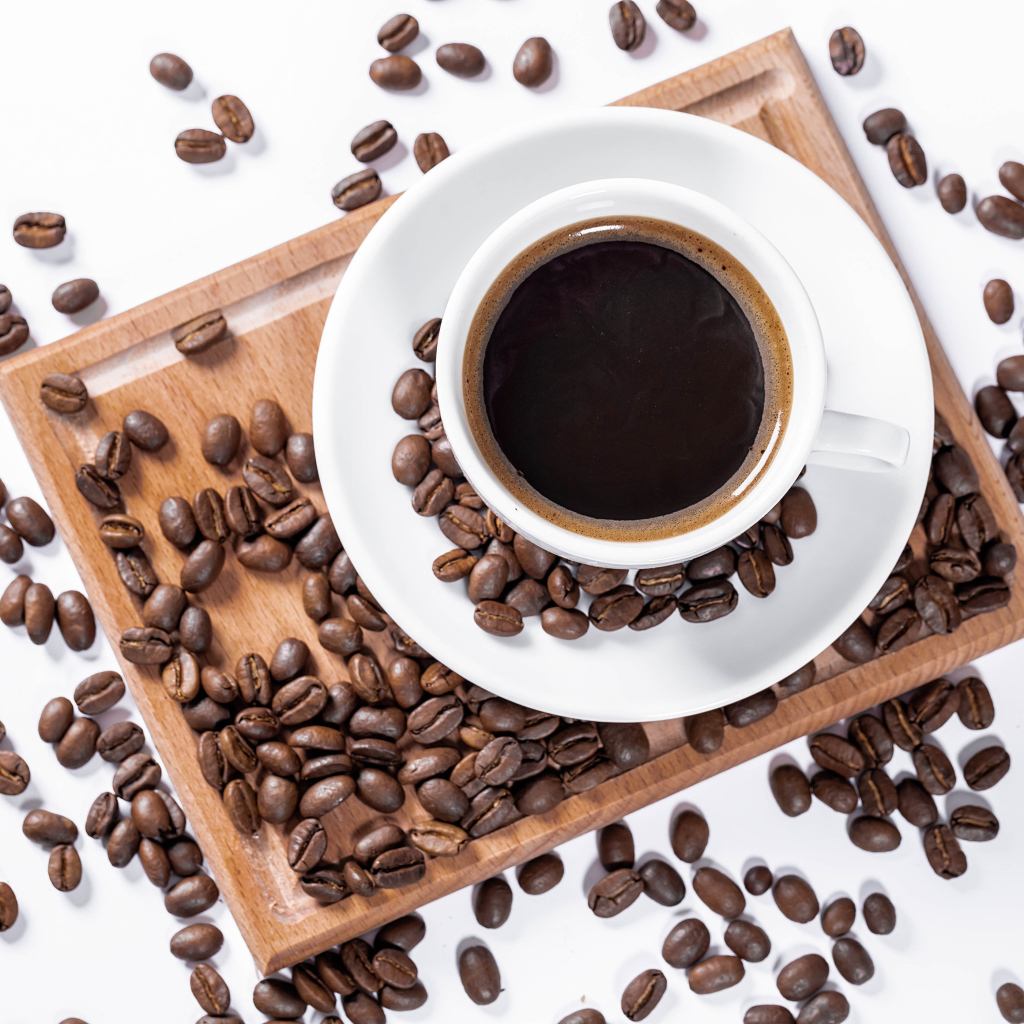 Белая чашка кофе на доске с кофейными зернами