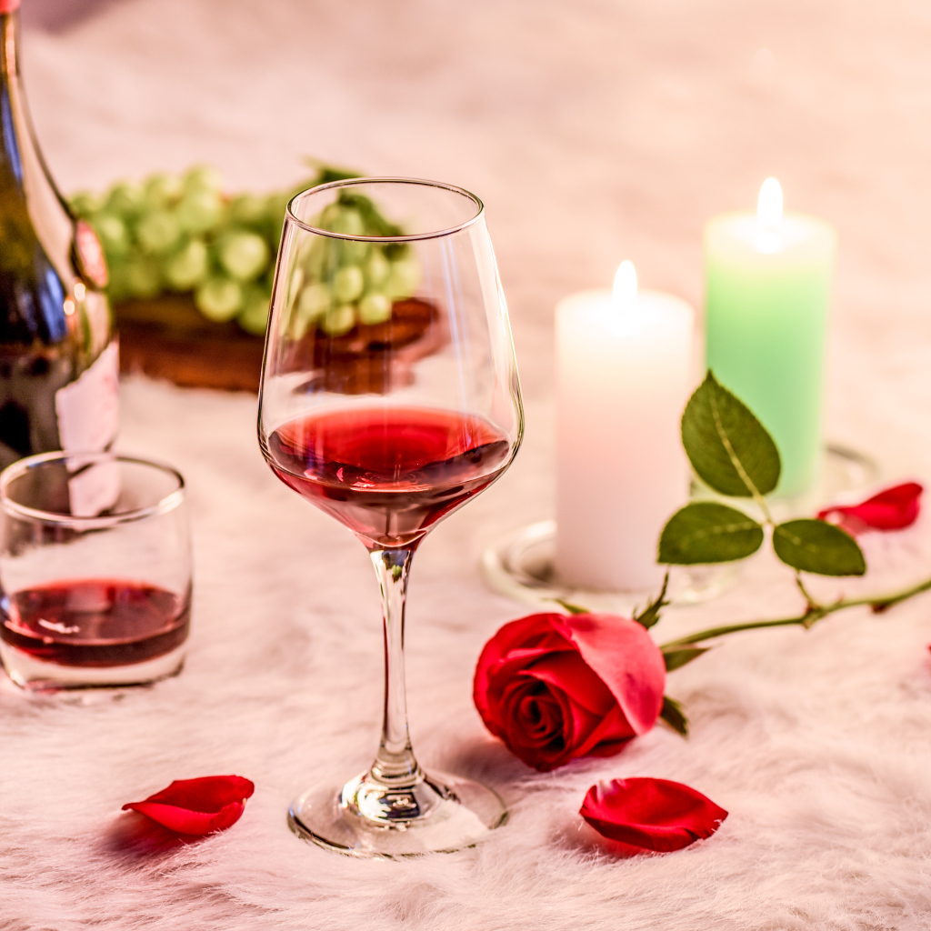 Вино на кровати с розой, виноградом и зажженными свечами