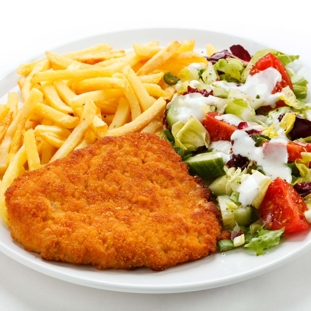 Отбивная с картофелем фри и салатом на большой белой тарелке