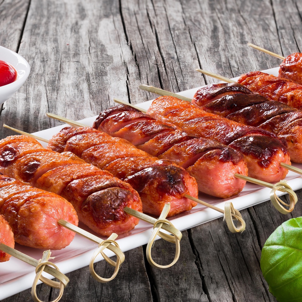 Сосиски гриль на шпажках на столе с соусом