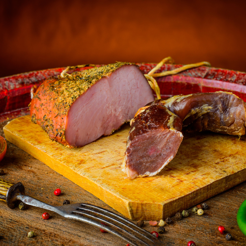 Ветчина и вяленое мясо на разделочной доске на столе с помидорами и горьким перцем 