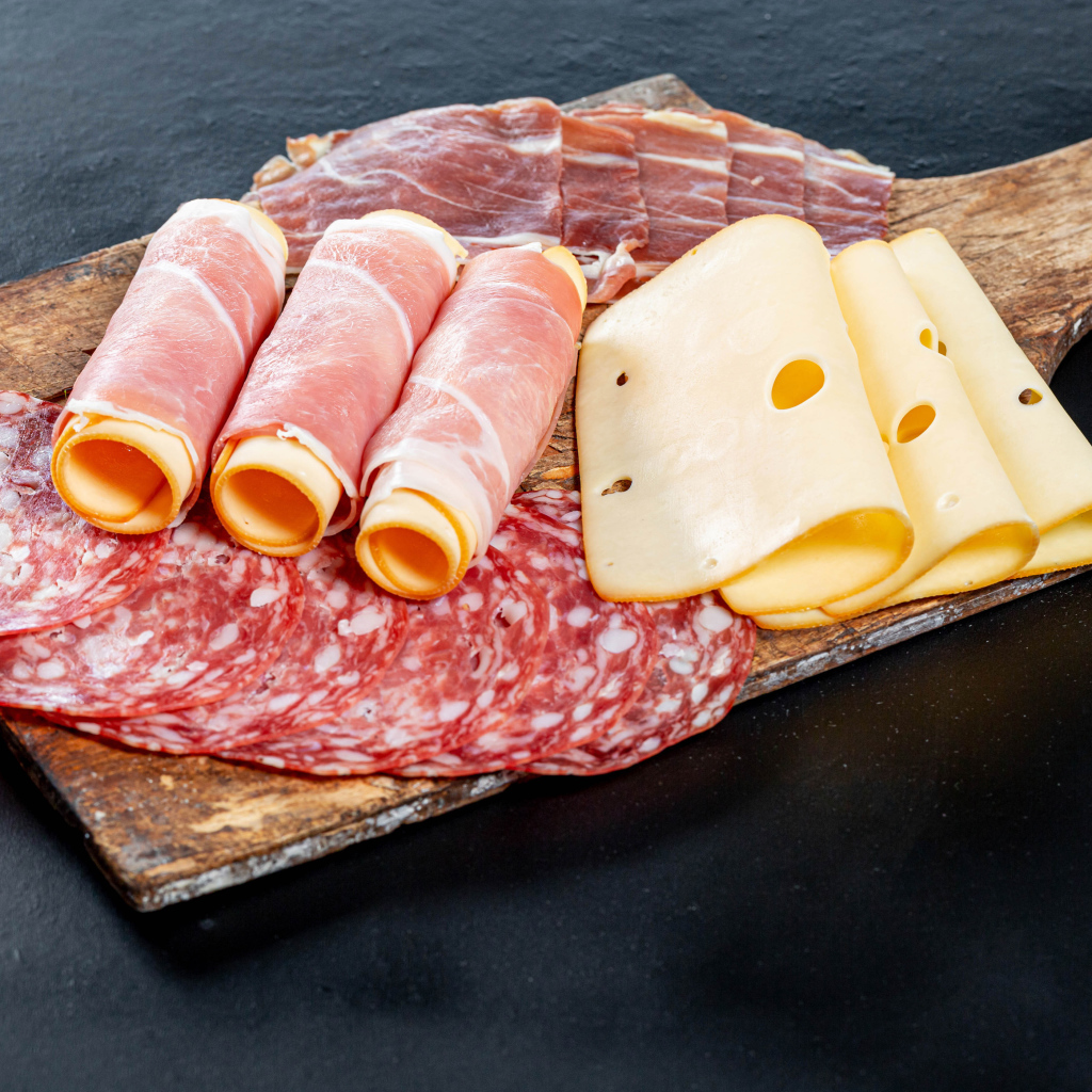 Ветчина на доске с колбасой и твердым сыром