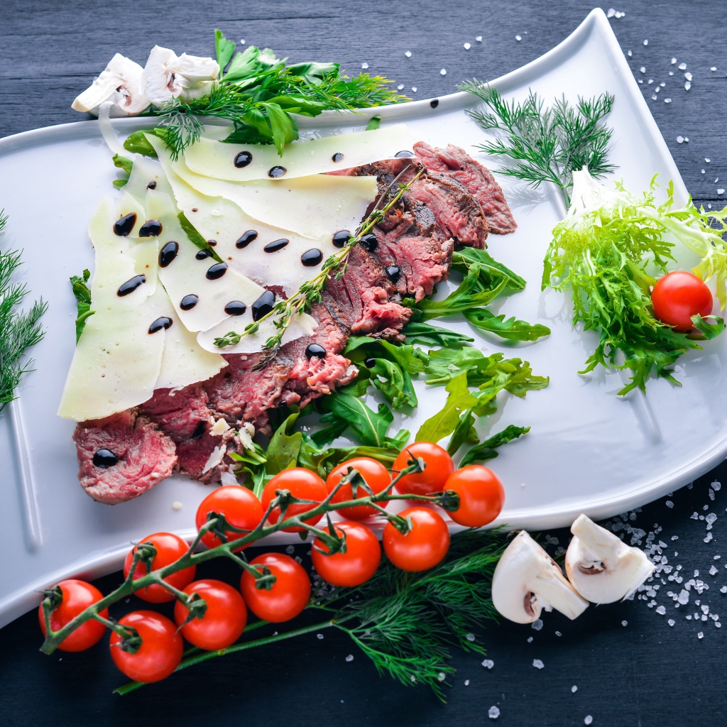 Мясо с сыром, овощами и зеленью на тарелке