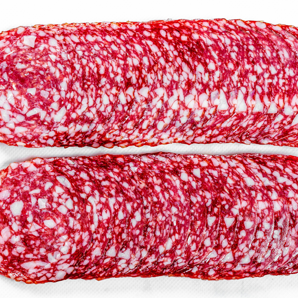 Колбаса салями нарезанная тонкими кусочками на белом фоне