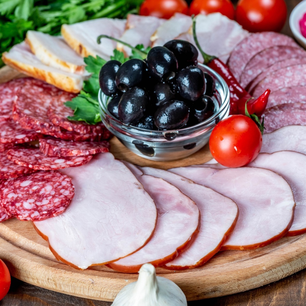 Колбасные продукты на доске с оливками